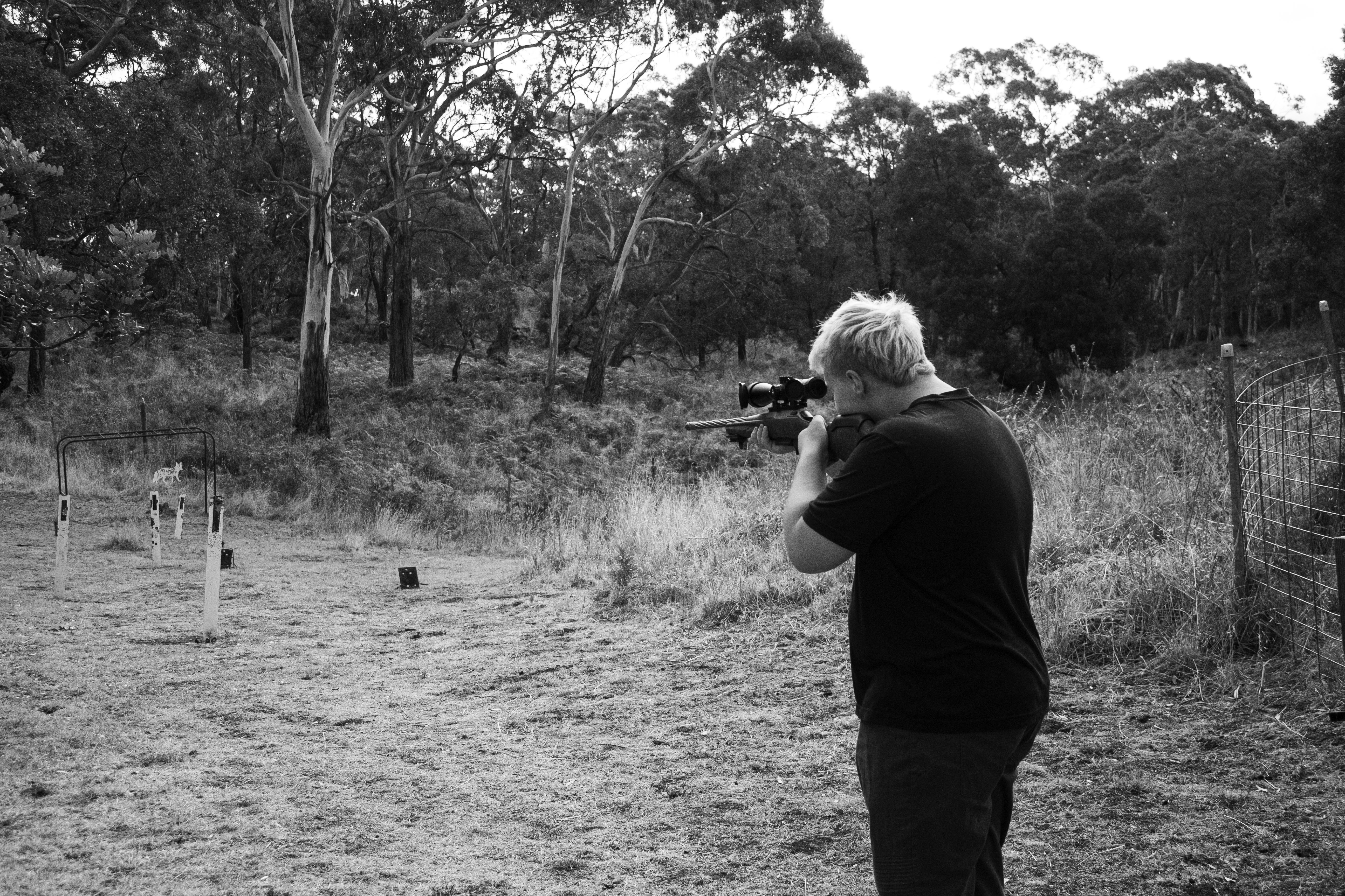 Young man aiming rifle in black and white, landscape