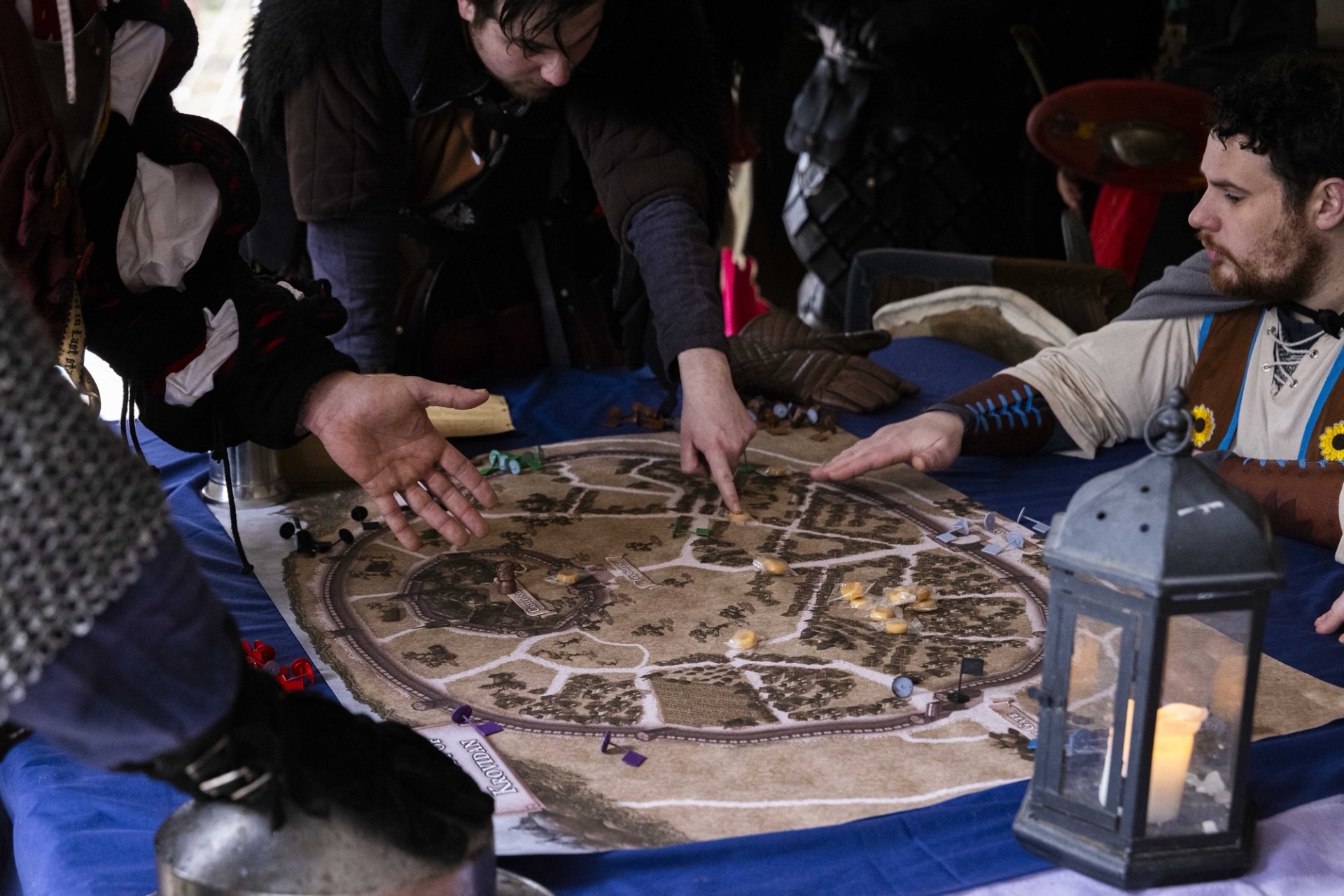 LARP players gathered around a detailed fantasy map, planning their next move in costume