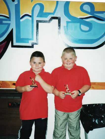 Chris Gillin and his brother as children, standing together in red shirts.