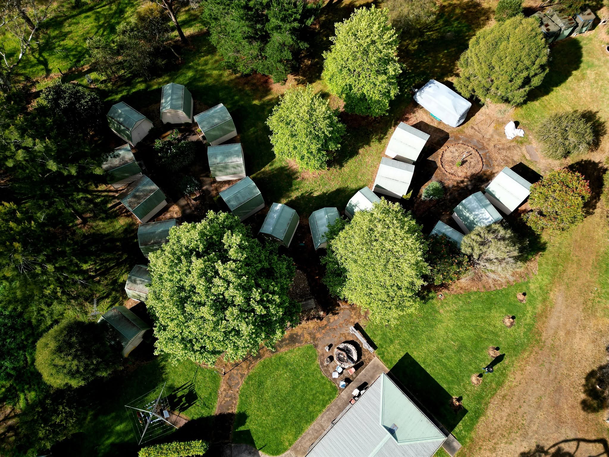 Aerial view of The Outside Inn near Wannon, showing cabin rooftops nestled among tall trees on a green property