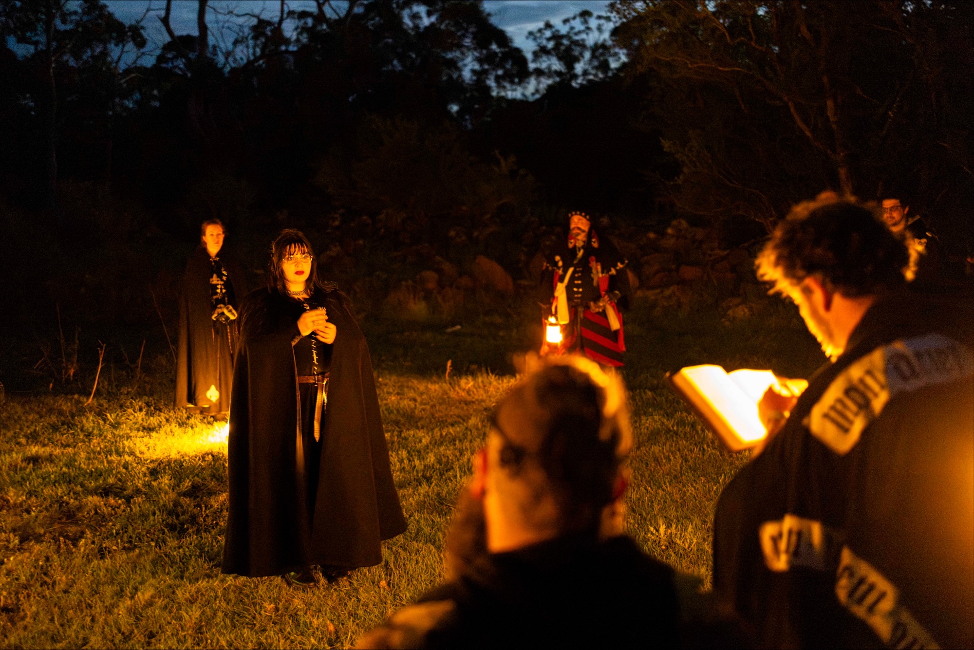 Swordcraft players gather around a lantern-lit nighttime scene in costume at the Pomborneit event